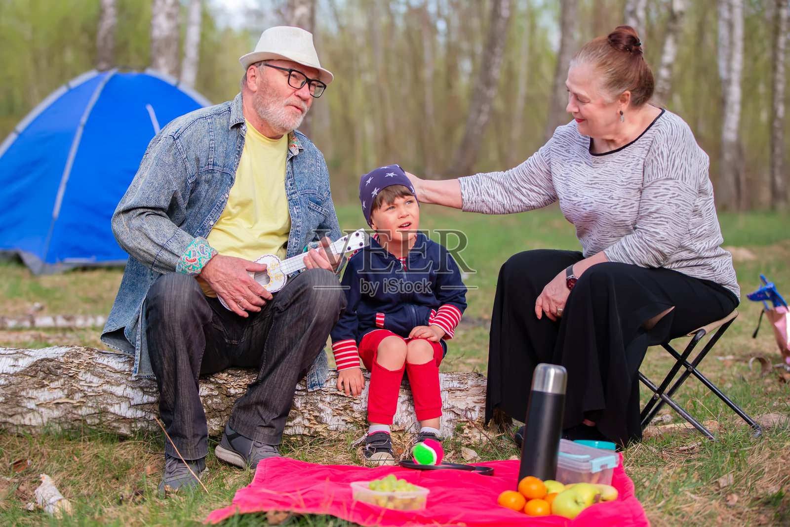奶奶、爷爷和孙子在树林里野餐。积极的家庭休闲活动。照片摄影图片