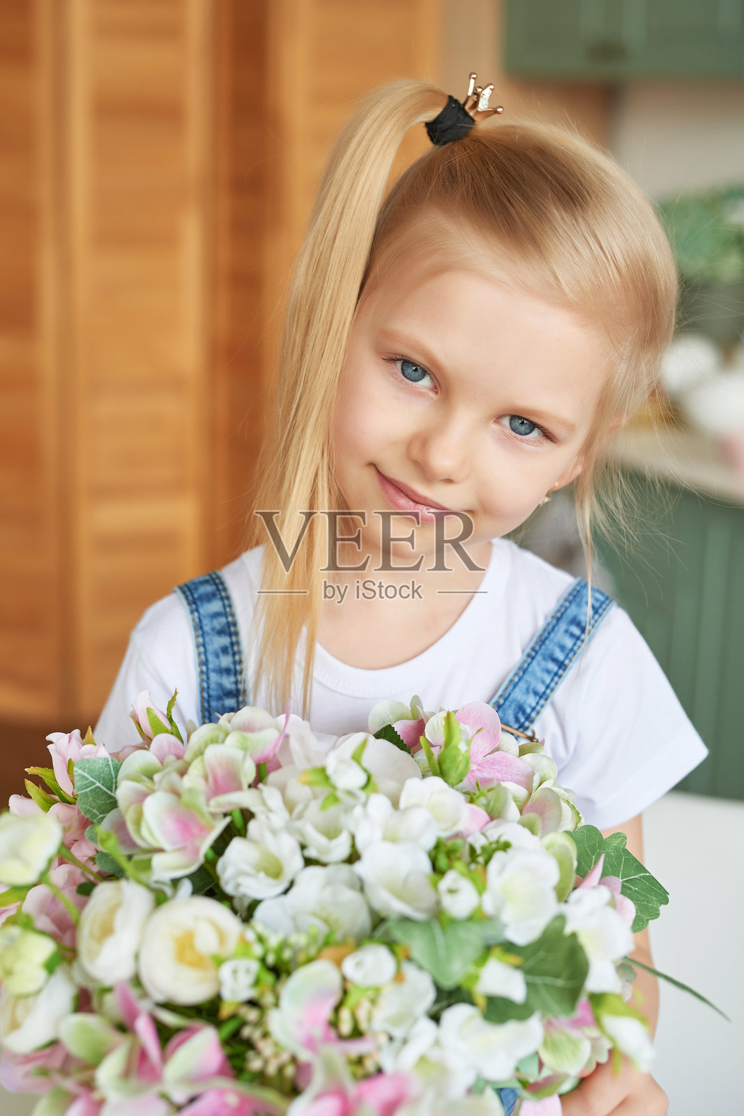 厨房里拿着花的小女孩。母亲节贺卡。普罗旺斯风格的厨房。3月8日国际妇女节。照片摄影图片