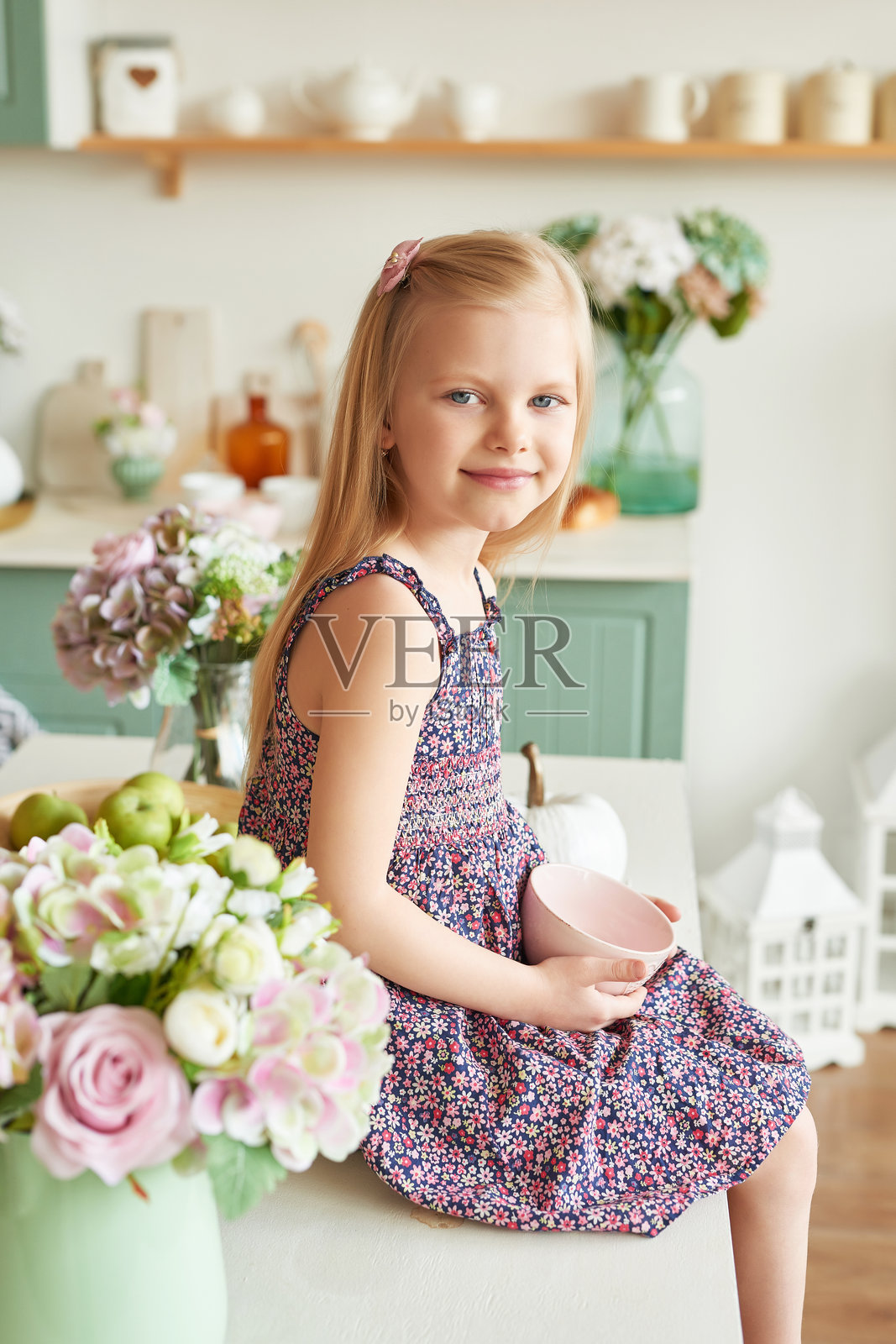 厨房里拿着花的小女孩。母亲节贺卡。普罗旺斯风格的厨房。3月8日国际妇女节。照片摄影图片