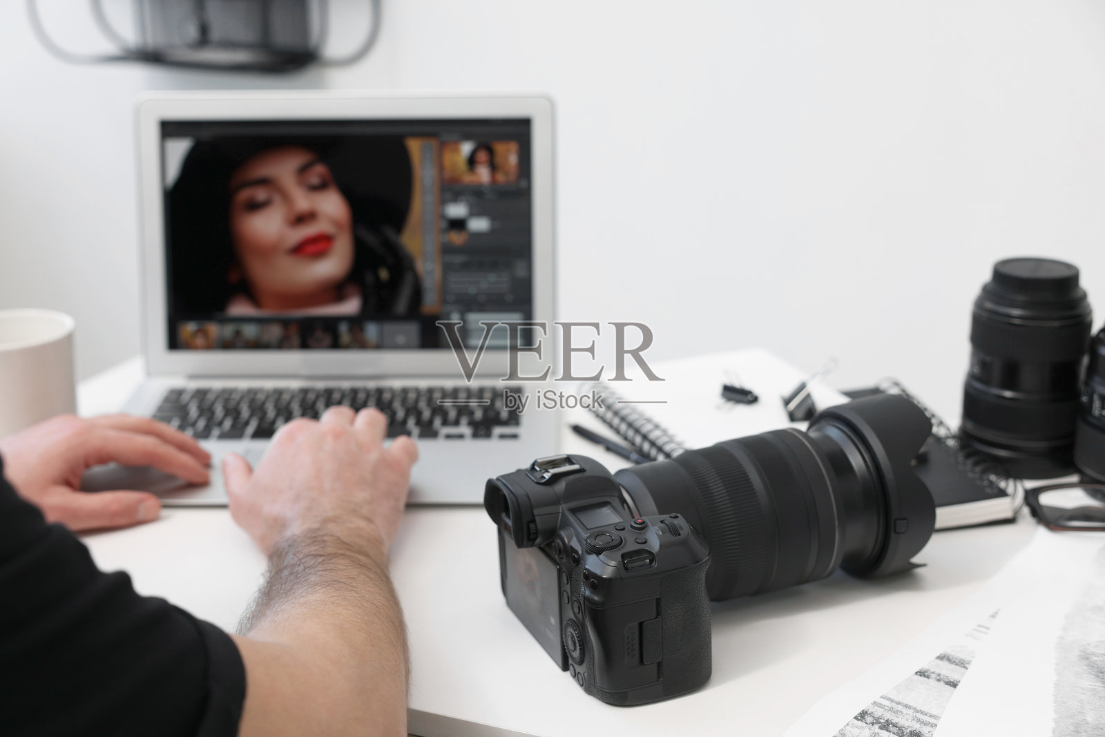 专业摄影师在桌子上使用笔记本电脑和数码相机，特写镜头照片摄影图片