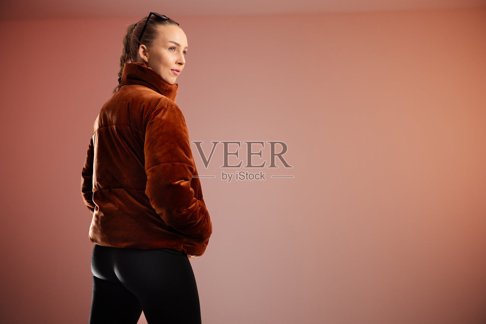 年轻女性穿着棕色外套，在现代简洁的工作室环境中摆姿势照片摄影图片