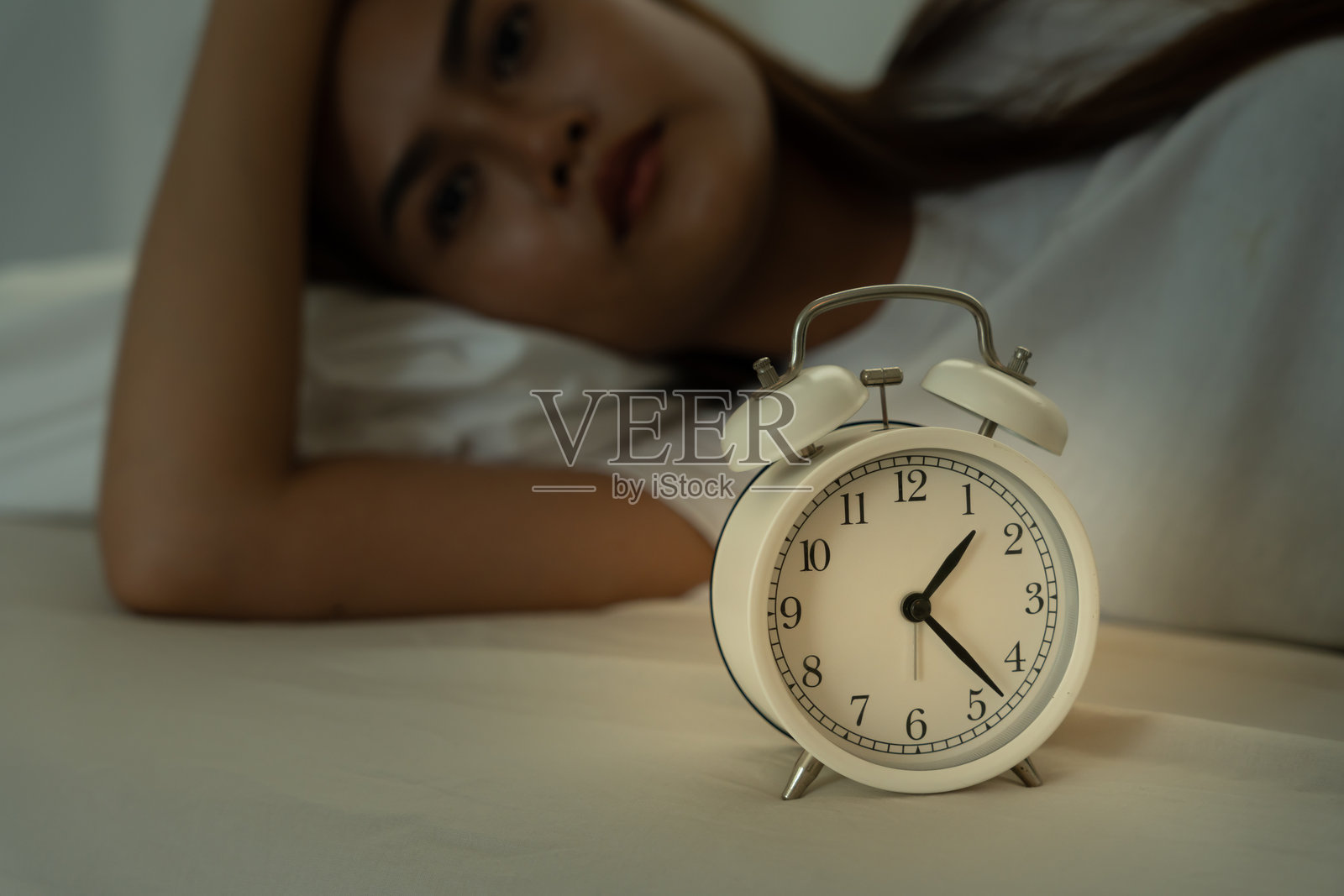 亚洲女性在床上熬夜，试图入睡，遭受失眠，感到害怕或做噩梦，显得悲伤、担忧和压力重重。疲惫不堪，头痛或偏头痛，在半夜醒来。照片摄影图片