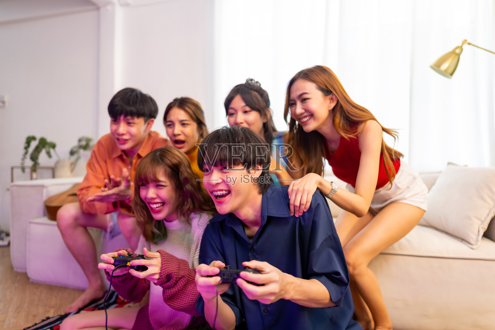 一群年轻的亚洲人在客厅一起玩视频游戏。照片摄影图片