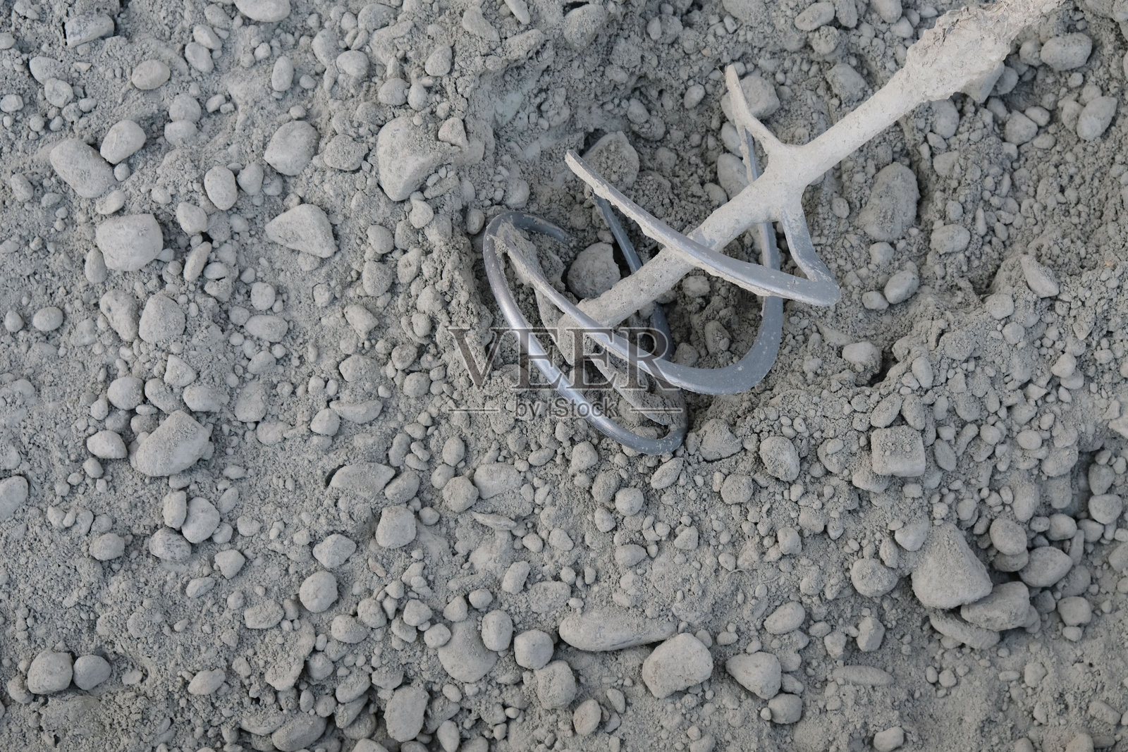 用干沙和碎石混合物以及水泥制备自制混凝土砂浆的过程，手持式建筑搅拌机在混合砂浆的容器中的特写。照片摄影图片