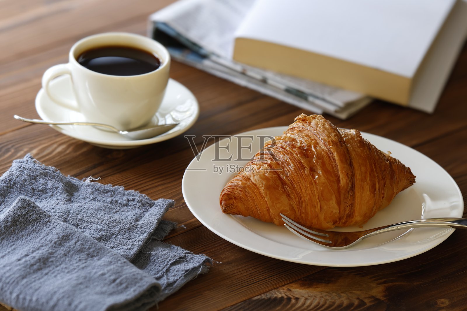 白盘子里的可颂面包和叉子照片摄影图片