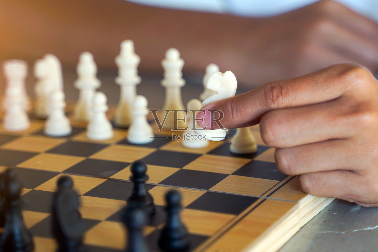 棋手的手特写，按照计划移动棋子以击败对手。柔和而选择性的焦点。照片摄影图片