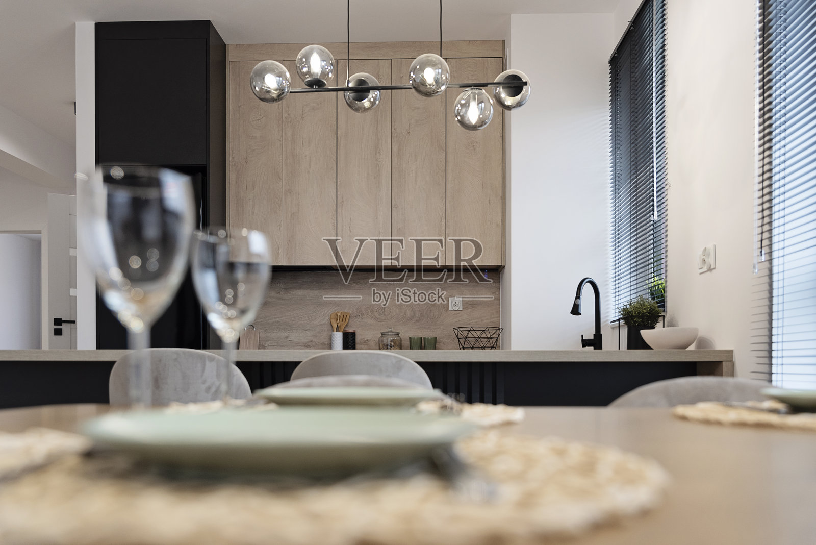 室内厨房，配有餐桌、椅子和餐具摆放。室内建筑风格，木质家具和窗帘。房地产。照片摄影图片