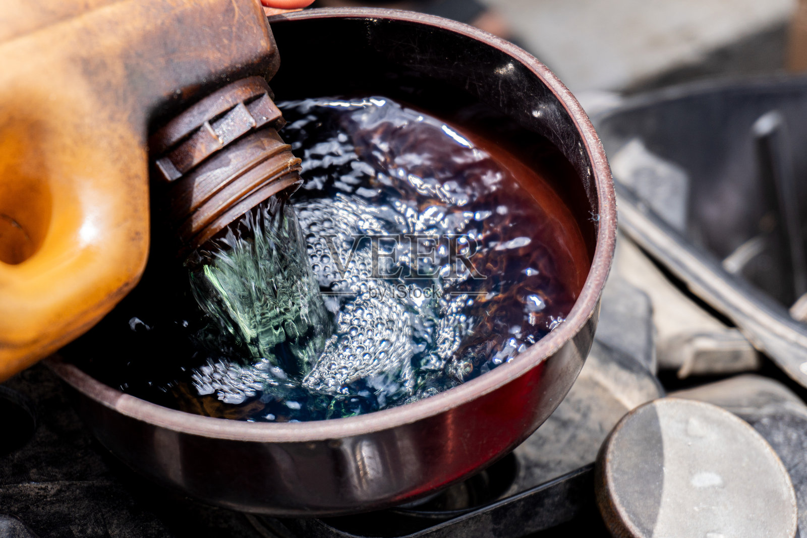 有人正在给摩托车油箱加油或汽油。街头加油商。照片摄影图片