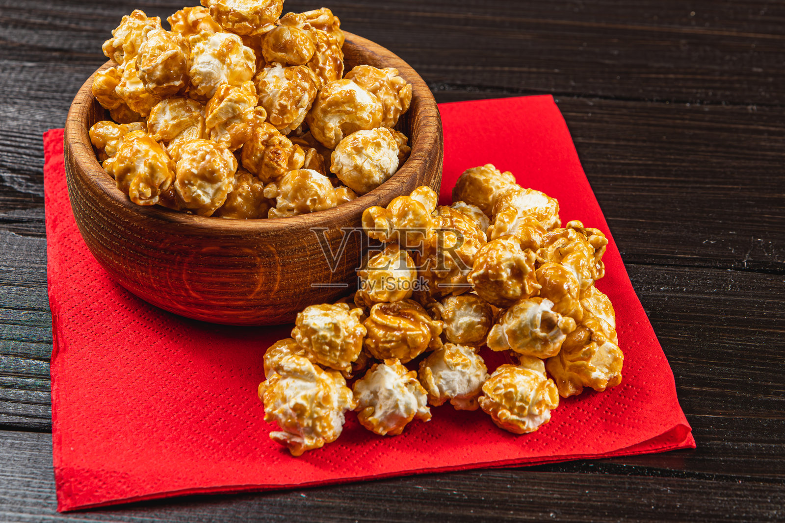 小吃，电影概念，木碗中的焦糖爆米花放在红色餐巾上照片摄影图片