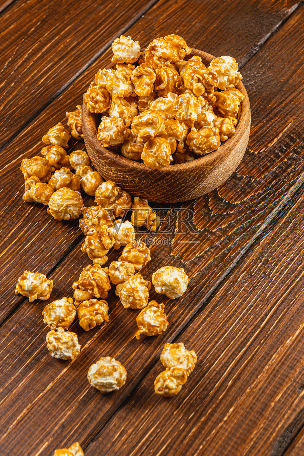 小吃，电影概念，木碗中的焦糖爆米花放在木桌上照片摄影图片