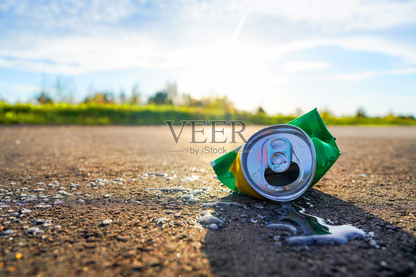 破损的汽水罐在沥青路面上，饮料洒落一地。照片摄影图片