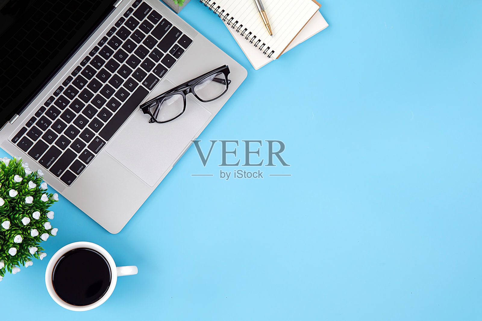 现代办公室桌面俯视图，包含笔记本电脑、咖啡杯、眼镜、笔记本和办公用品，适合工作背景概念。照片摄影图片