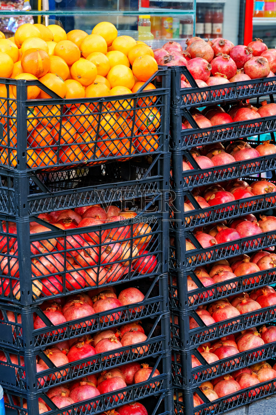 街边的商店柜台上摆放着新鲜的水果，箱子里有石榴和橙子。照片摄影图片