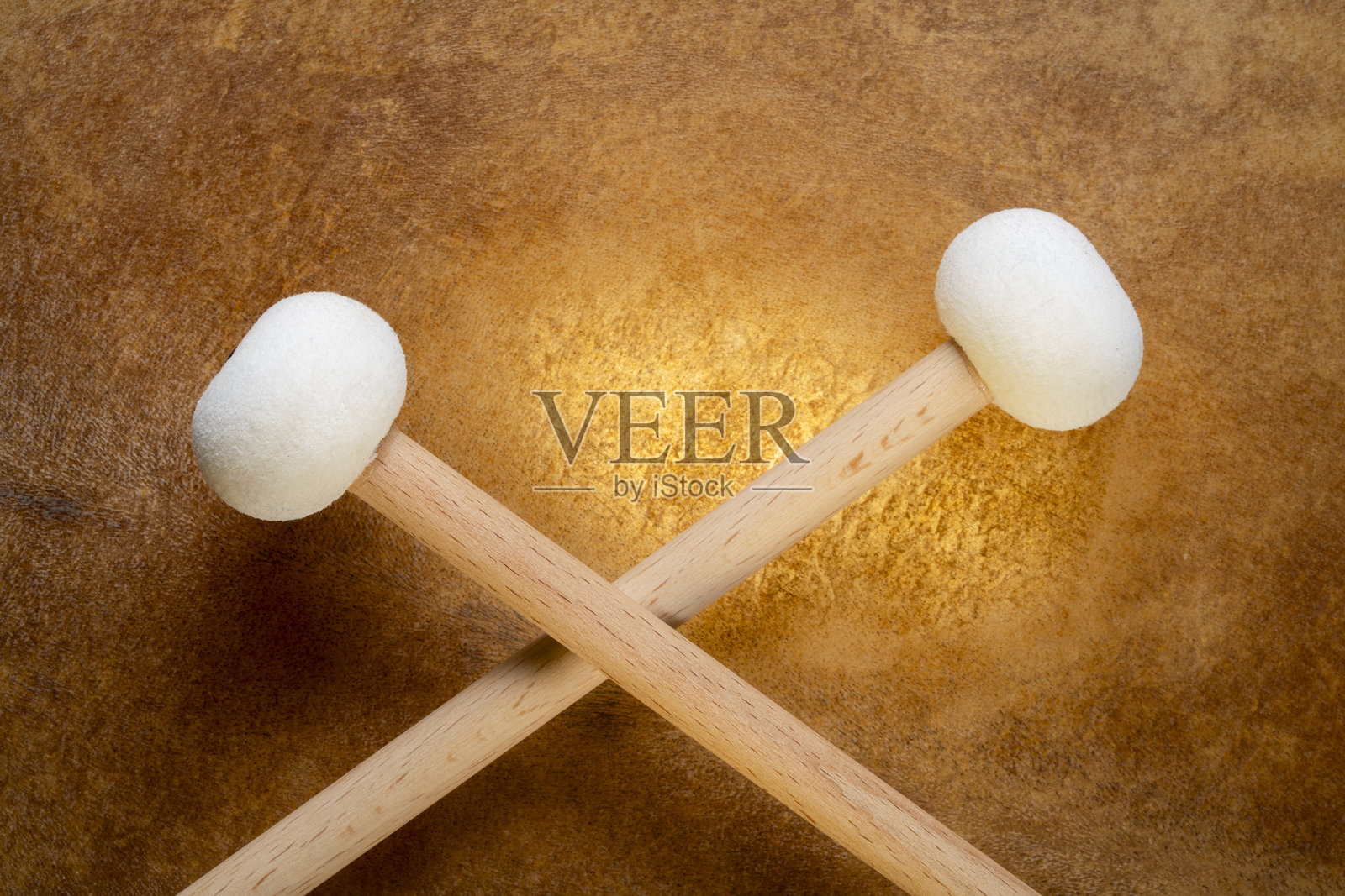 柔软的毛毡定音鼓槌与背光的羊皮鼓面照片摄影图片