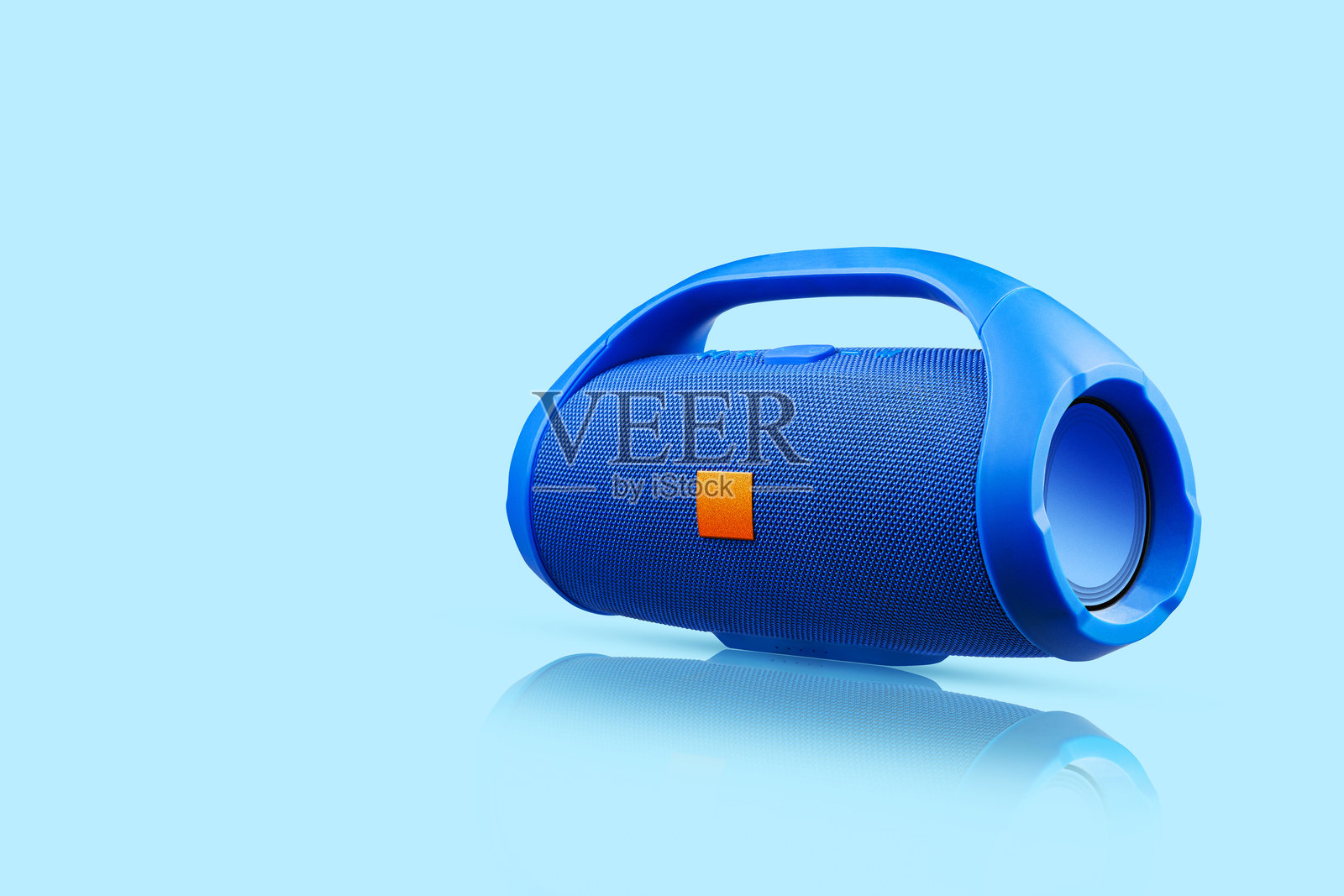 蓝色便携式无线蓝牙音箱，映衬在蓝色背景上。播放音乐的设备。音乐。照片摄影图片
