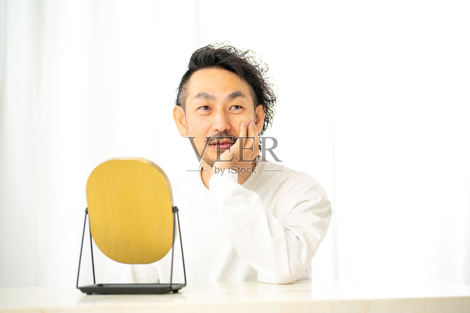 一名日本男子在镜子前检查自己的皮肤照片摄影图片