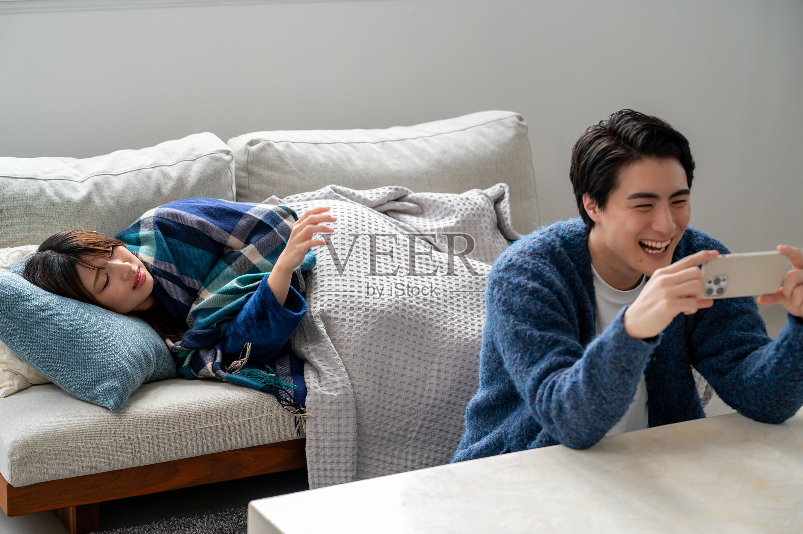 一名日本男子在照顾生病的女性时使用智能手机。照片摄影图片