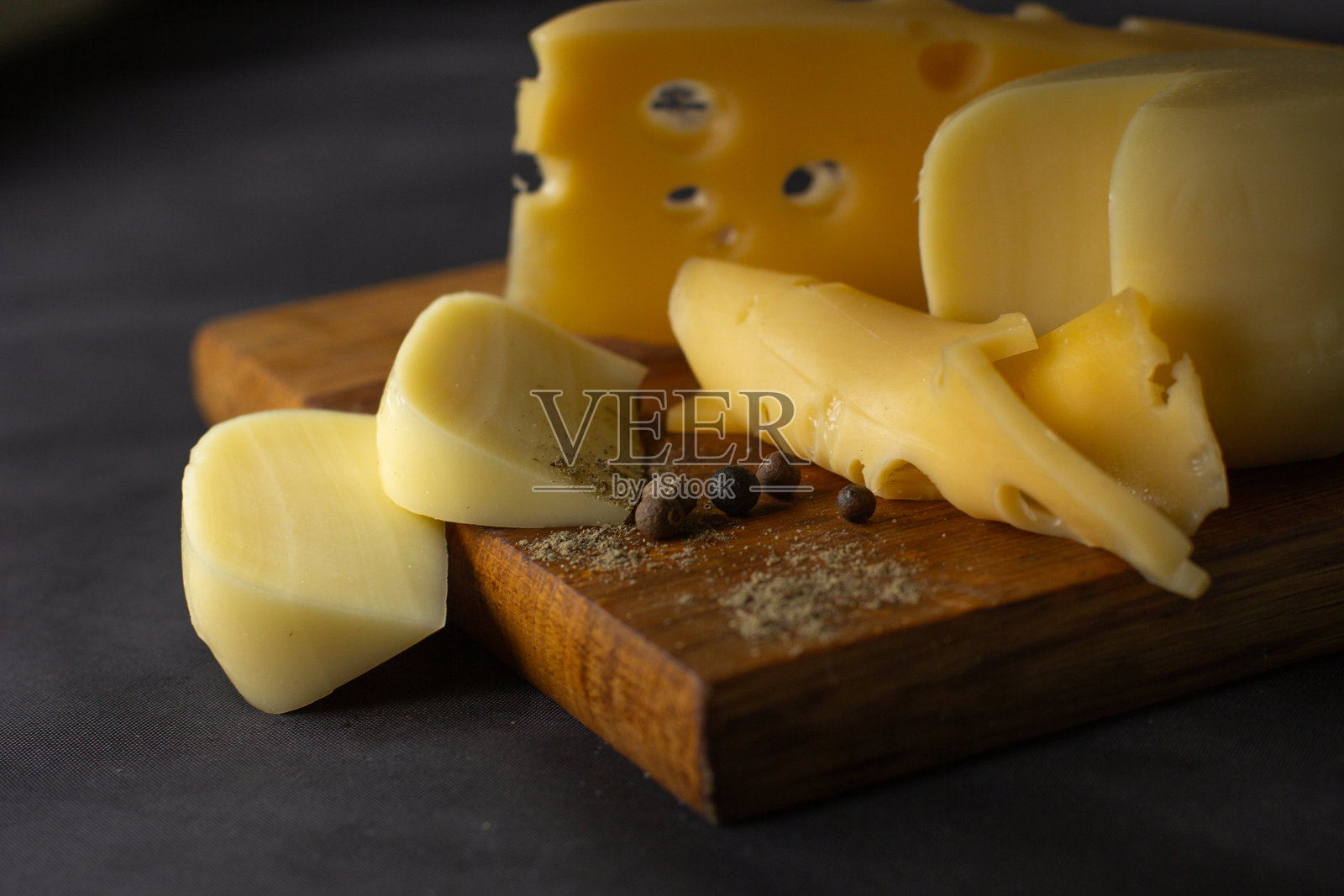 不同种类的奶酪放在黑色背景的木板上。奶酪产品切成块放在切菜板上。照片摄影图片