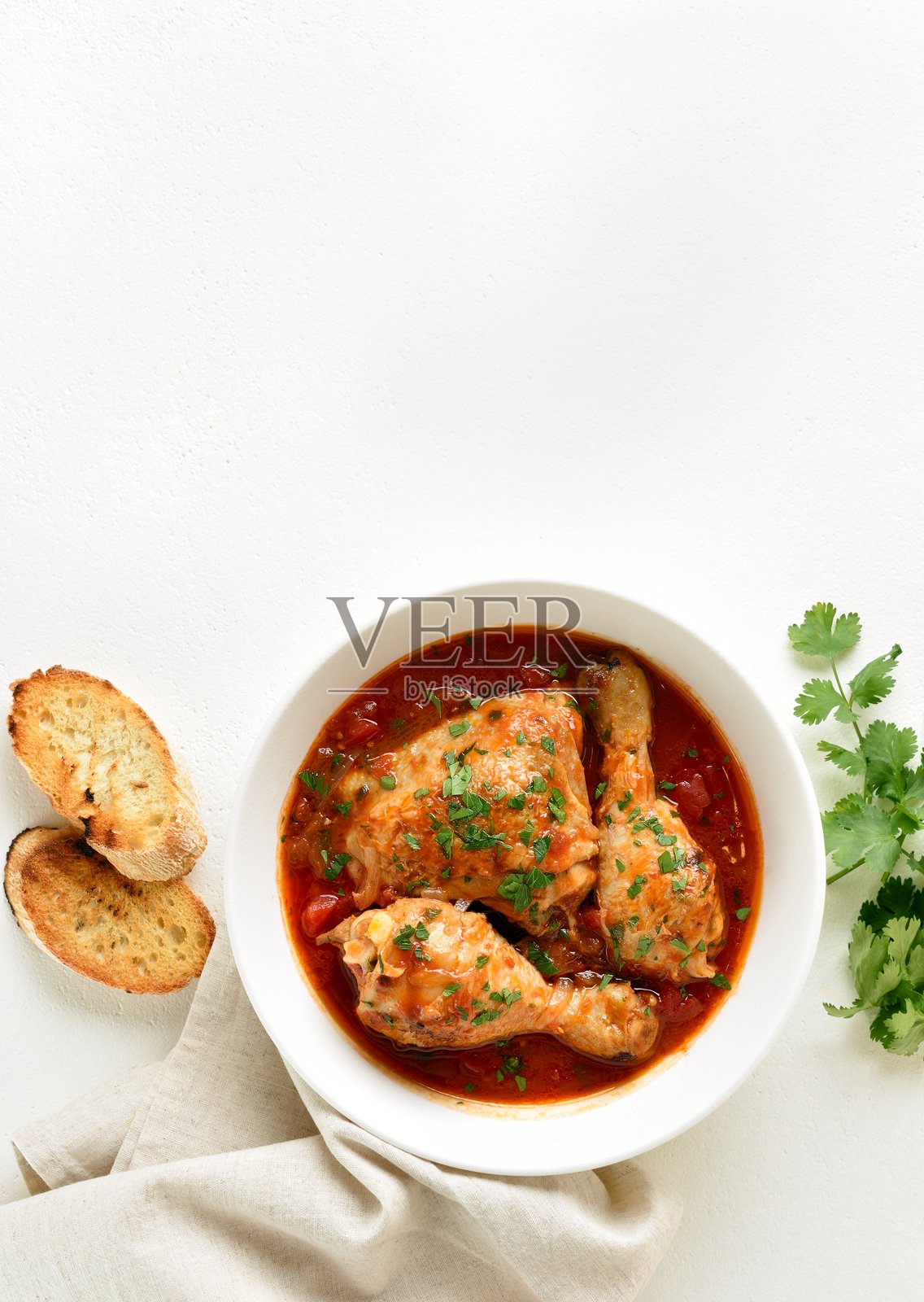 在碗里用西红柿和香草炖鸡，白色的背景和复制空间照片摄影图片