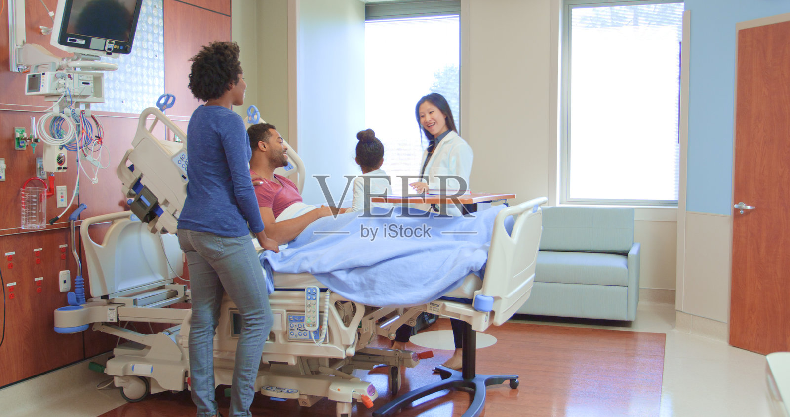 穿着白大褂的女医生与探望住院父亲的家人会面照片摄影图片