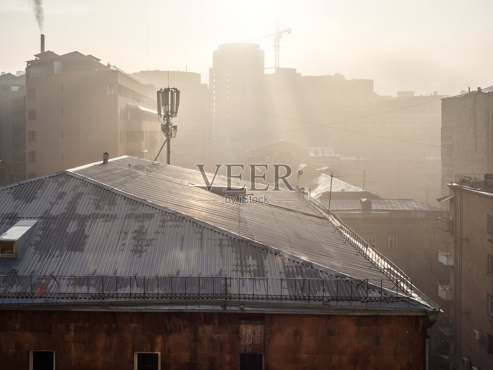 阳光透过雾霾照亮房屋的屋顶照片摄影图片