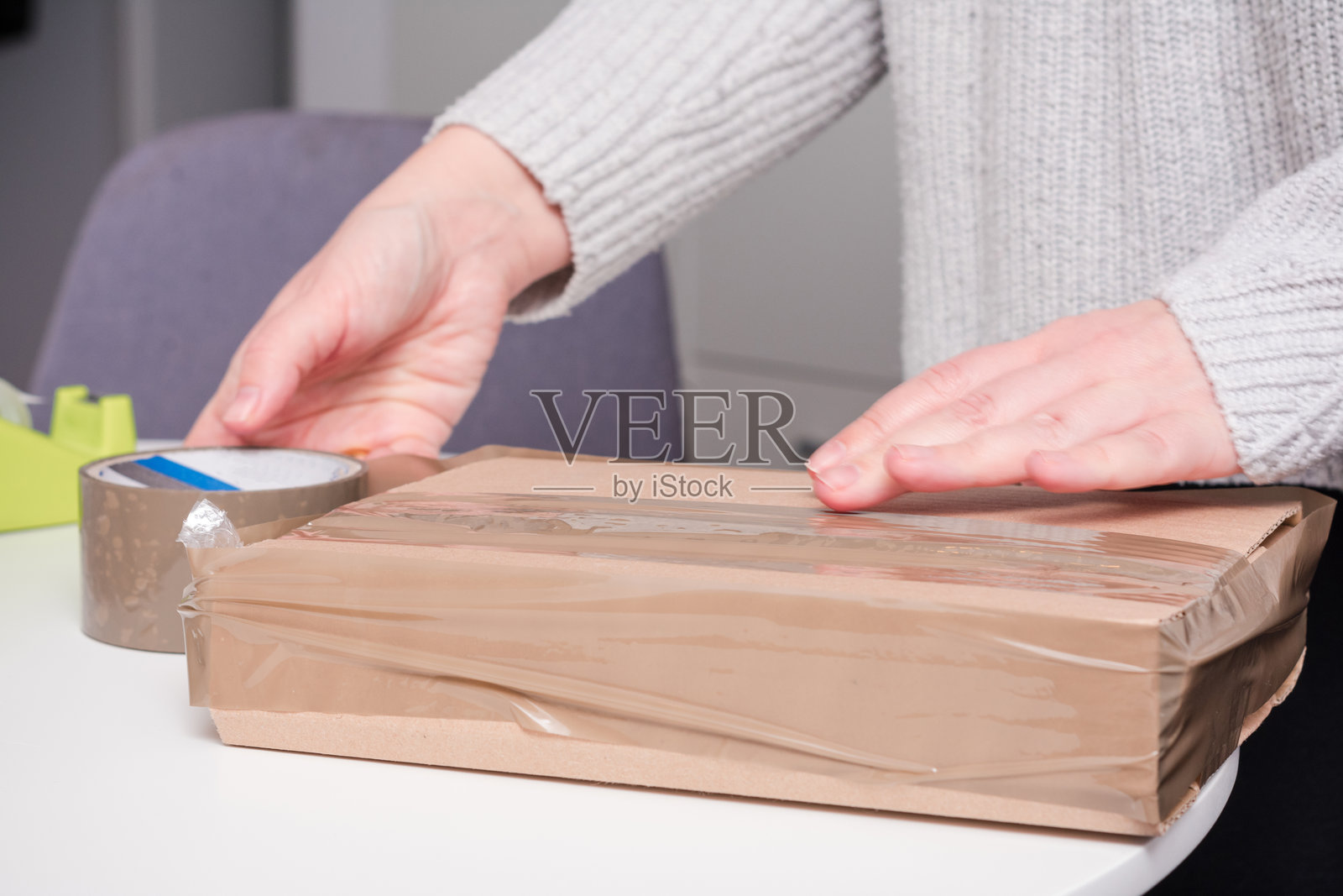 女人正在用胶带包装一个棕色盒子照片摄影图片