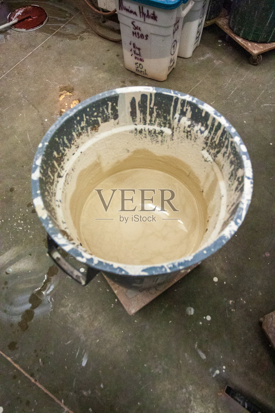 陶艺工作坊中陶瓷釉料的涂抹过程与容器中的陶瓷浆料照片摄影图片