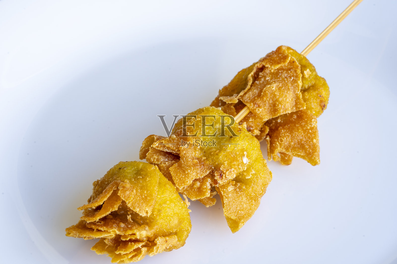 白色盘子上的炸馄饨特写，旁边放着筷子照片摄影图片