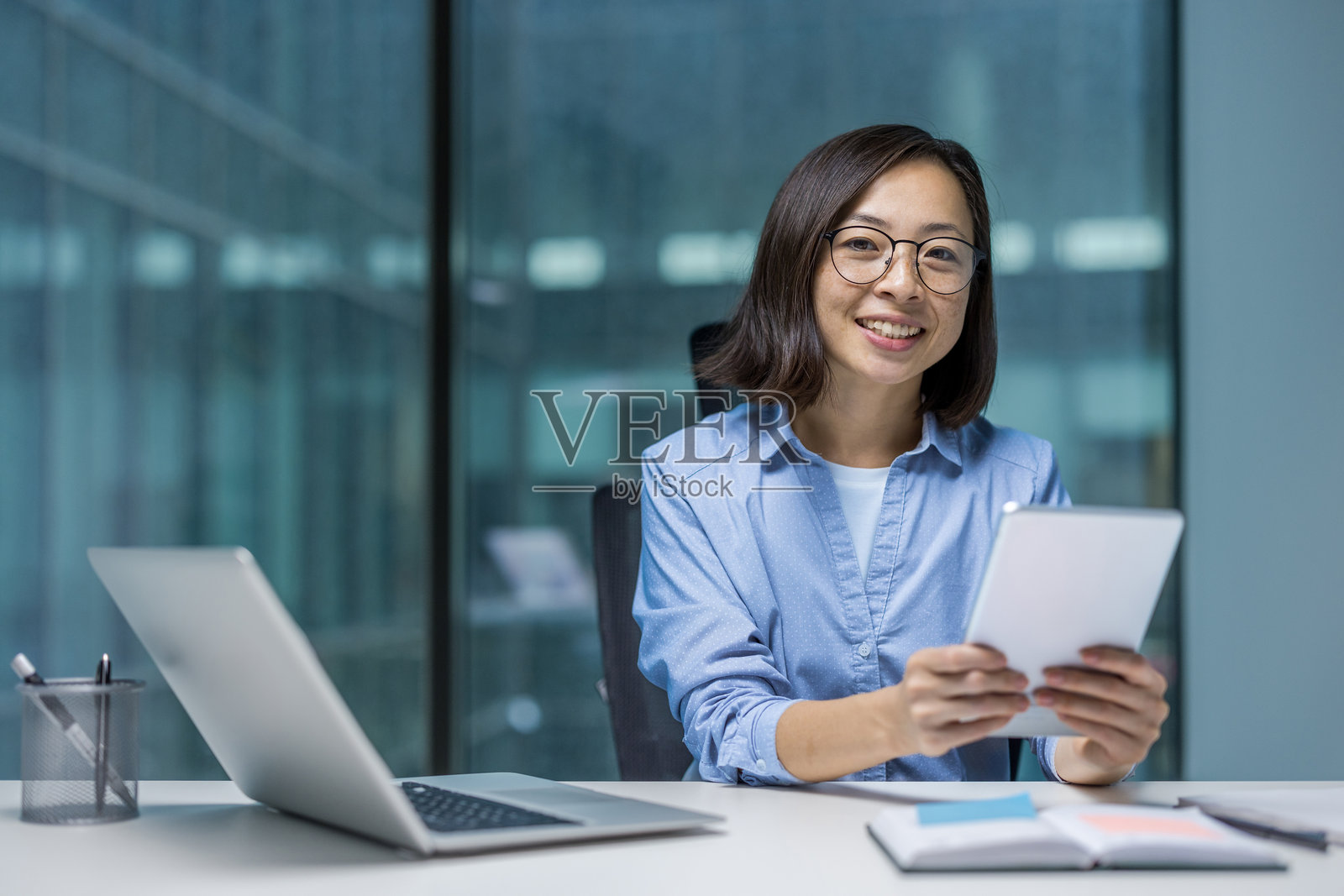 亚洲女性商务人士在现代办公桌上使用平板电脑照片摄影图片