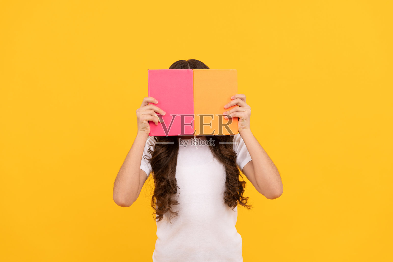 准备学习的学校少女躲在作业本后面，教育照片摄影图片