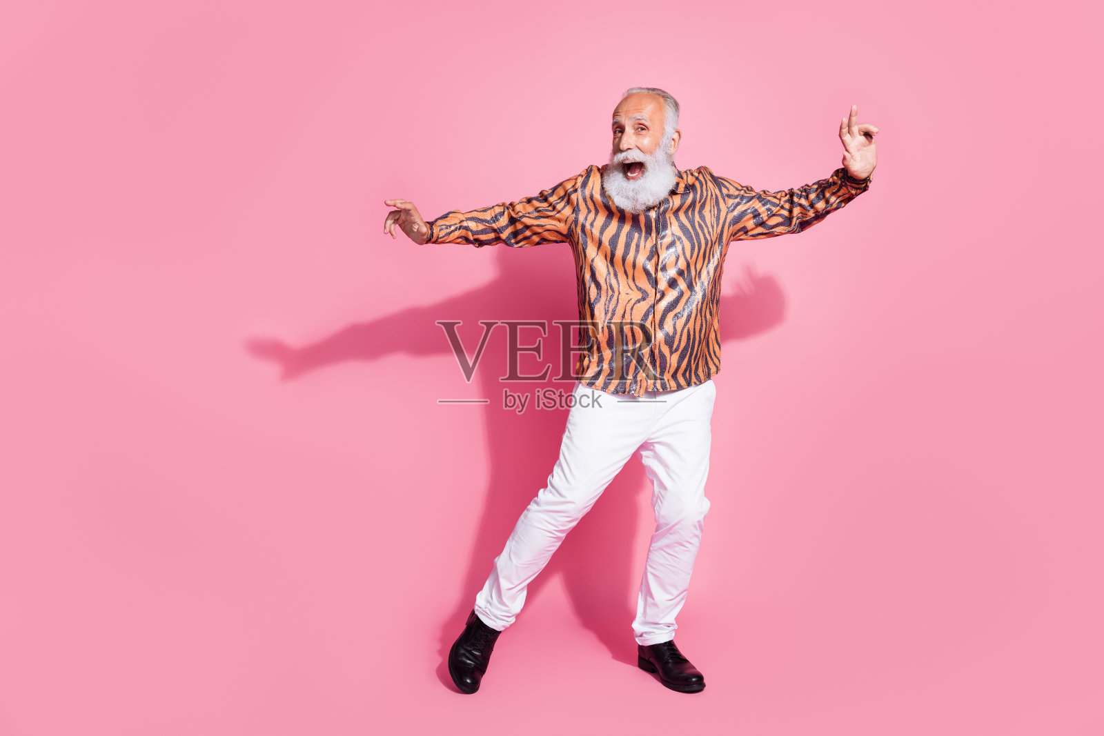兴奋的老人在柔和色彩背景下穿着华丽的服装充满活力地跳舞照片摄影图片