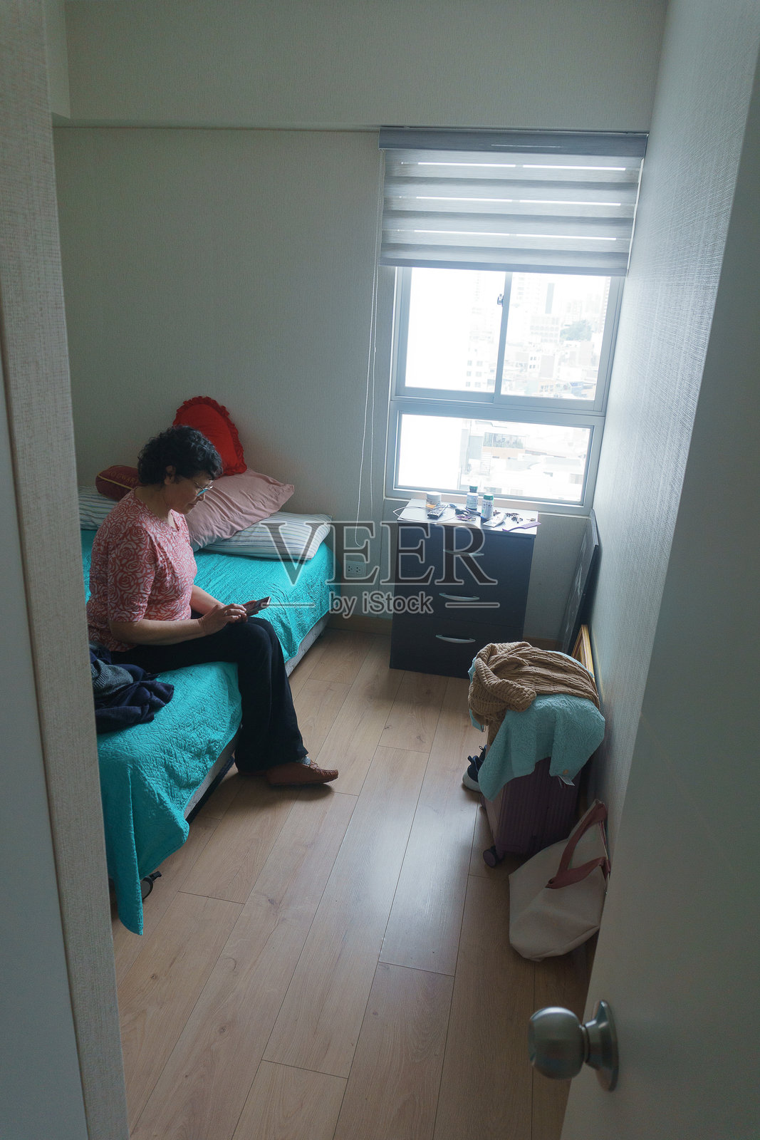 独自一人在房间里的老年女性看着手机。照片摄影图片