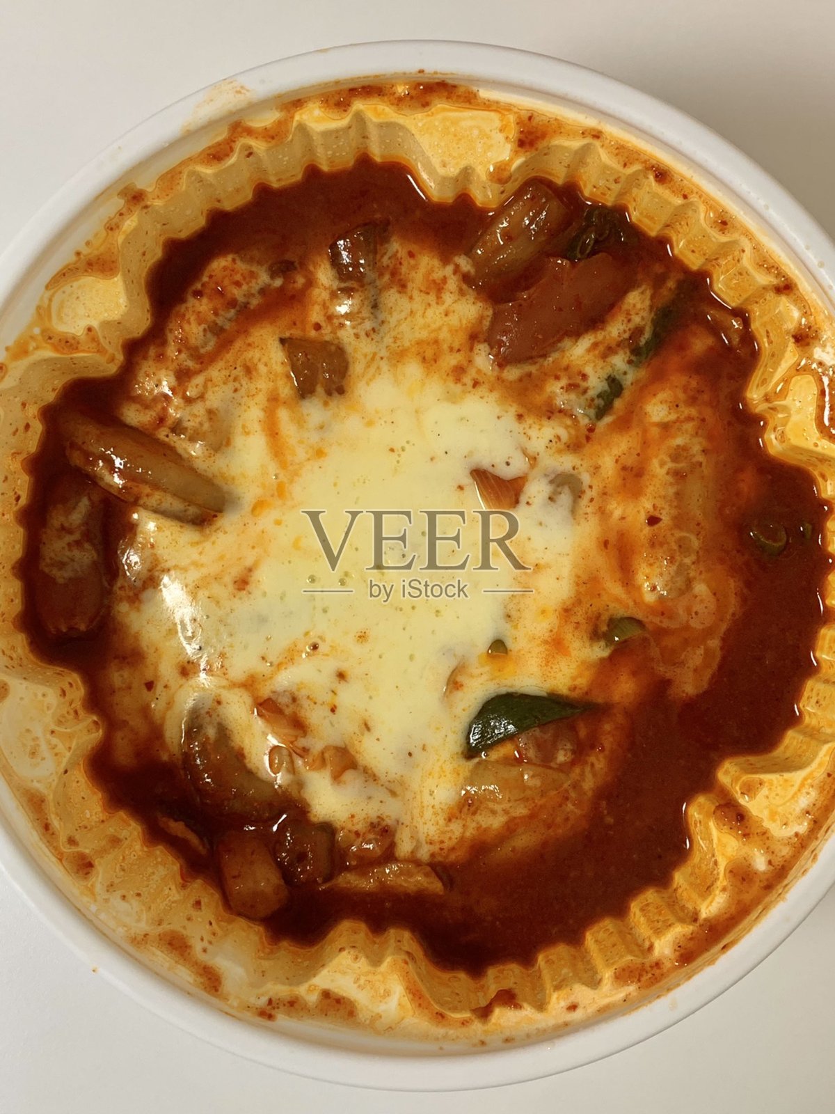 辣炒年糕是一道辛辣的韩国米糕菜肴，将有嚼劲的年糕与浓烈的酱汁相结合，通常搭配鱼饼和煮鸡蛋。因其火辣的口感和大胆的风味而闻名，是一种受欢迎的安慰食品。照片摄影图片