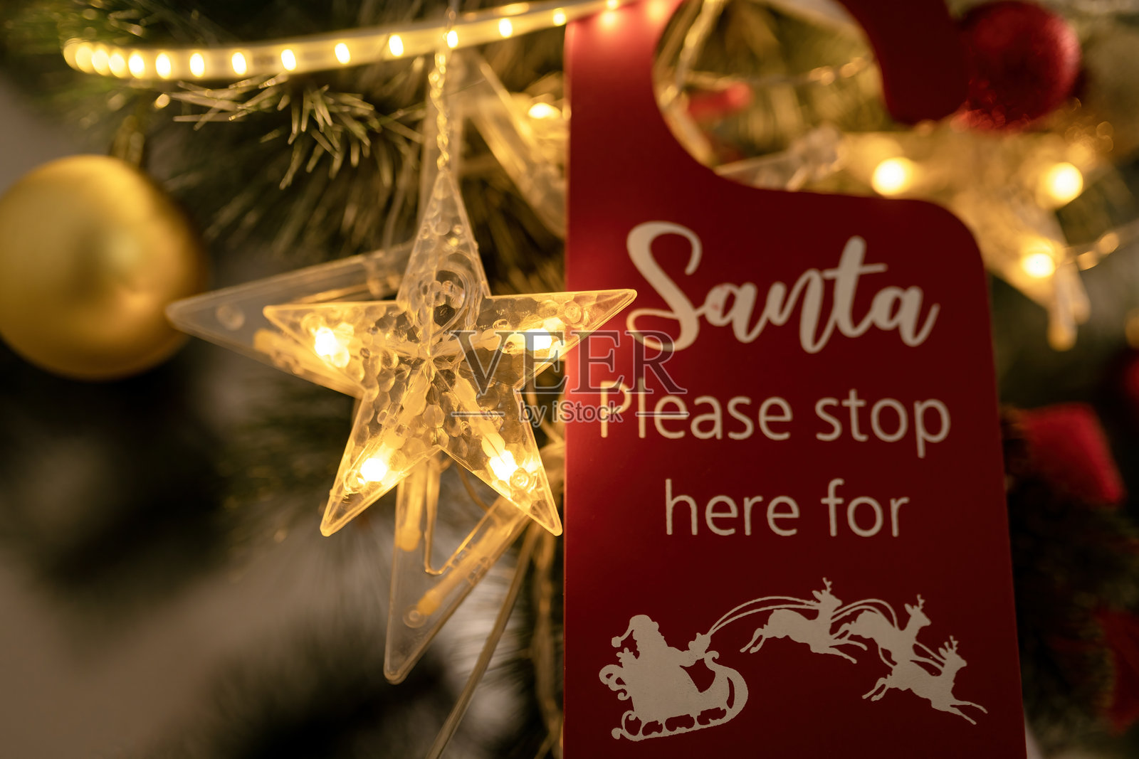 红色木质贺卡标签，配有LED灯星星和金色灯光虚化的松枝，节日问候卡，2024年圣诞背景图像，留有空白空间。照片摄影图片