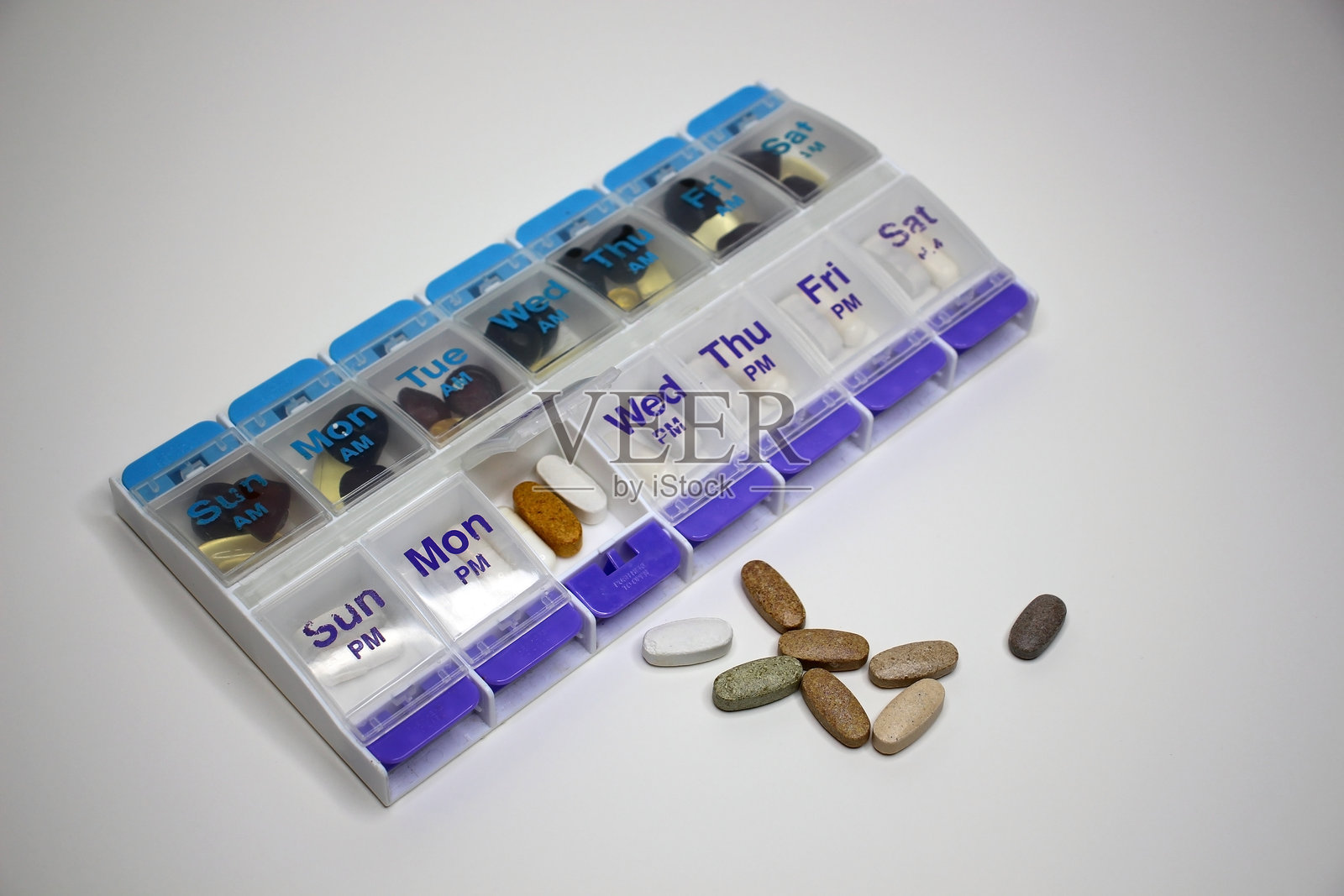 白色背景上的每周药丸整理器，内含补充剂和药物。照片摄影图片