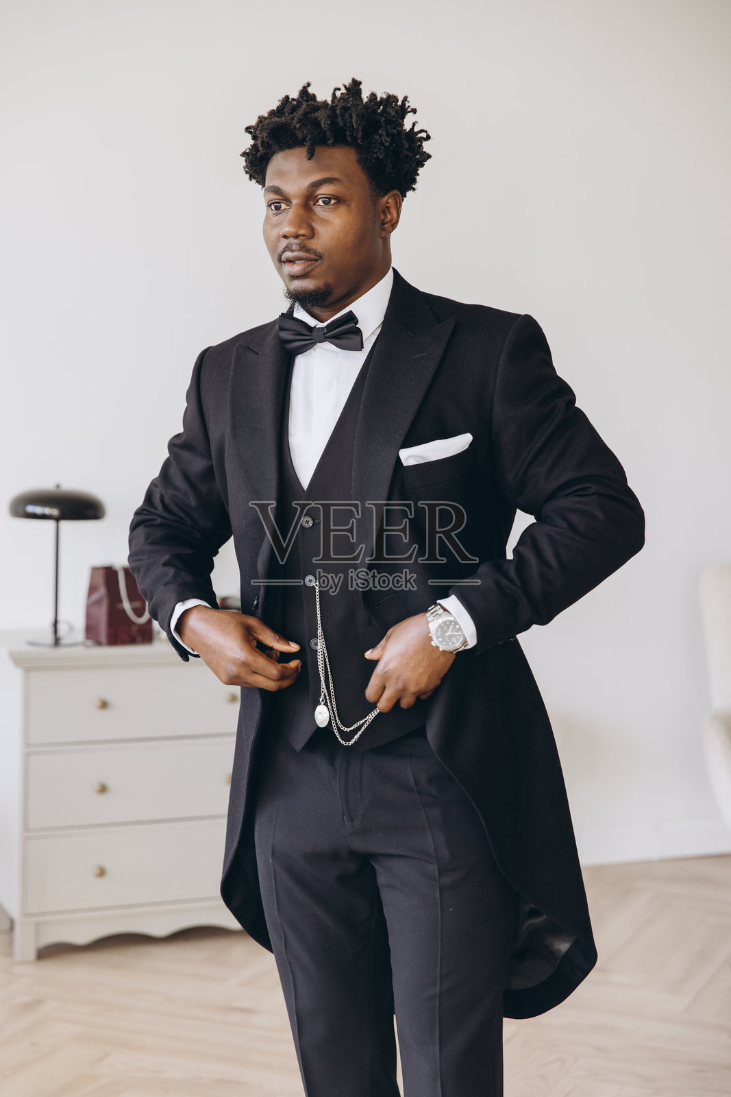 优雅的新郎在婚礼仪式前的房间里调整他的燕尾服照片摄影图片