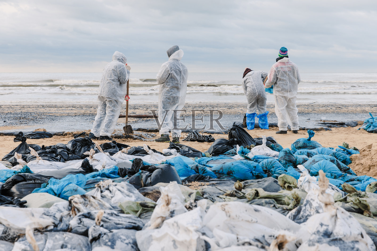 志愿者在油轮失事后清理海岸线上的石油污染照片摄影图片