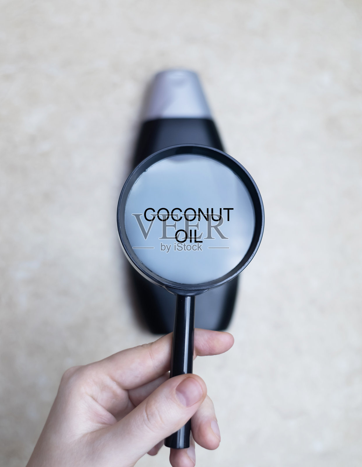 女性手握着一瓶洗发水，瓶身上写着成分 - 椰子油。安全有机洗发水成分的概念。照片摄影图片