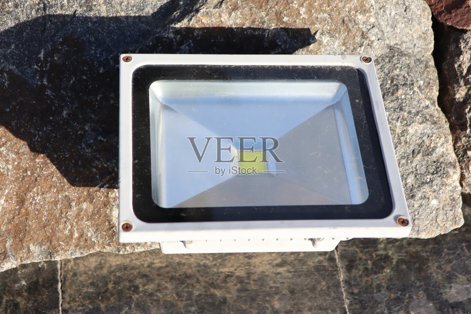 一个放置在岩石表面的LED泛光灯，理想用于有效照明户外空间照片摄影图片