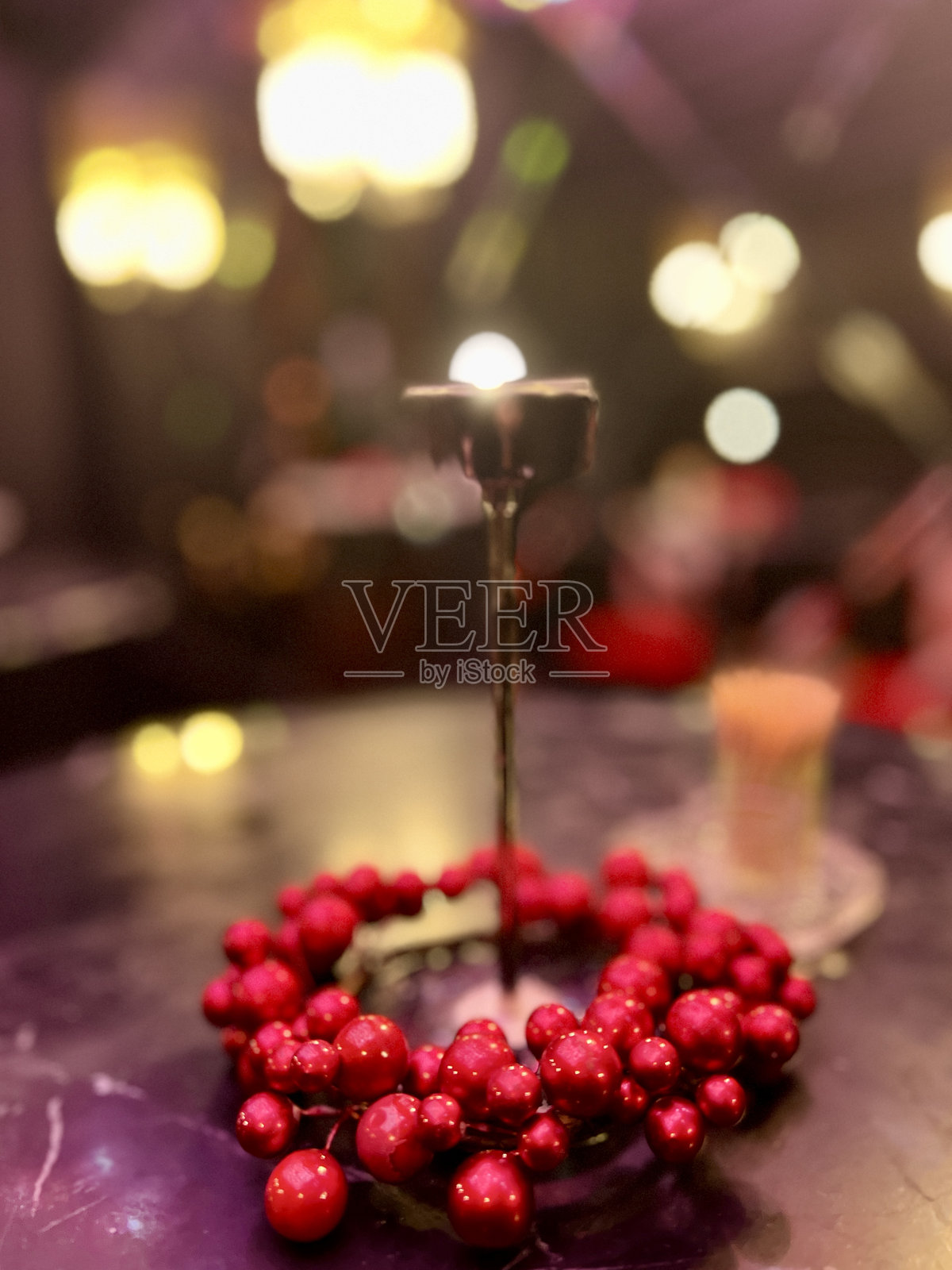 美丽的红色珠子作为咖啡馆圣诞假期桌上的装饰，背后有夜灯照耀。照片摄影图片