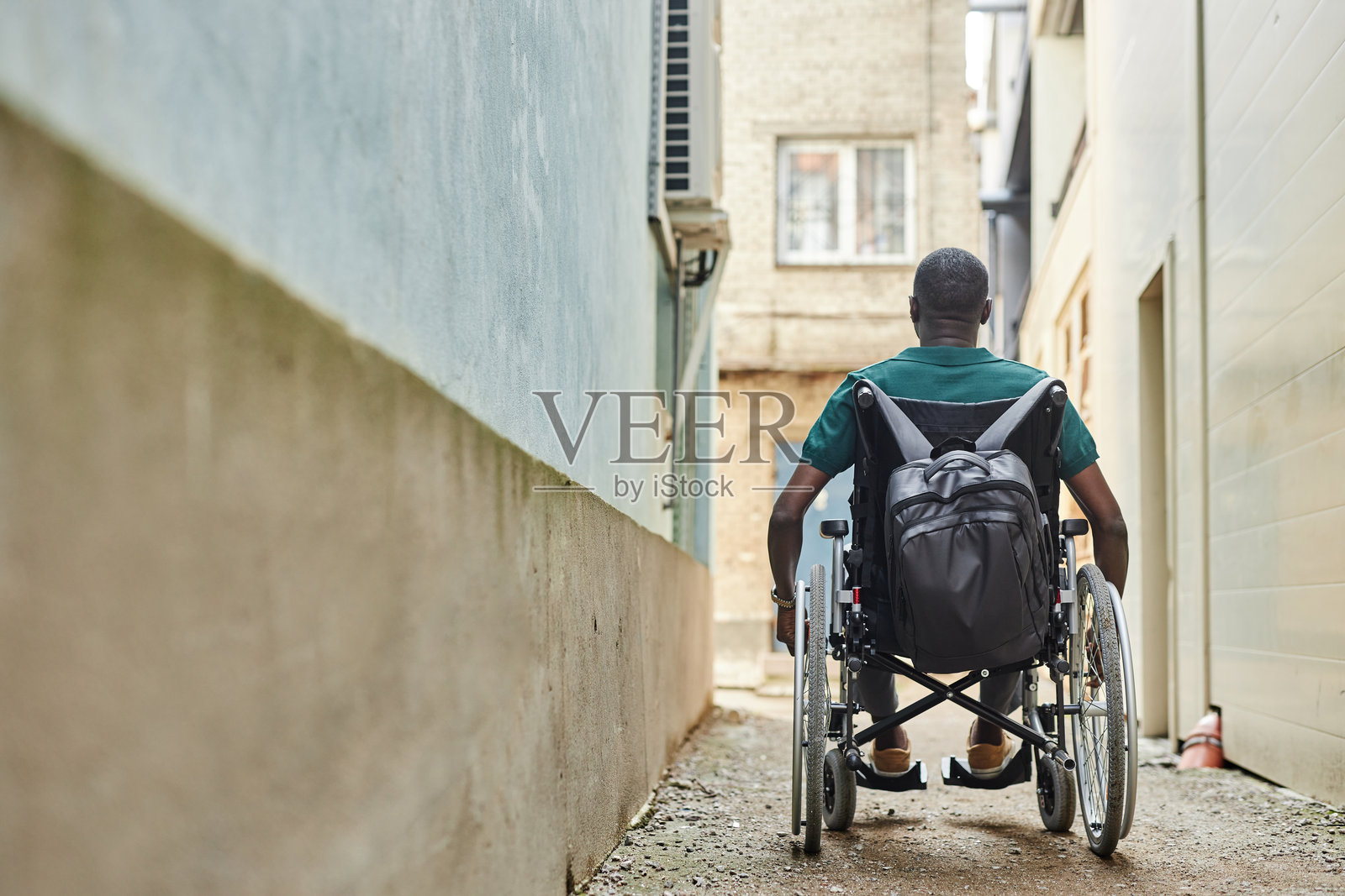 城市中坐在轮椅上的黑人男子背影照片摄影图片