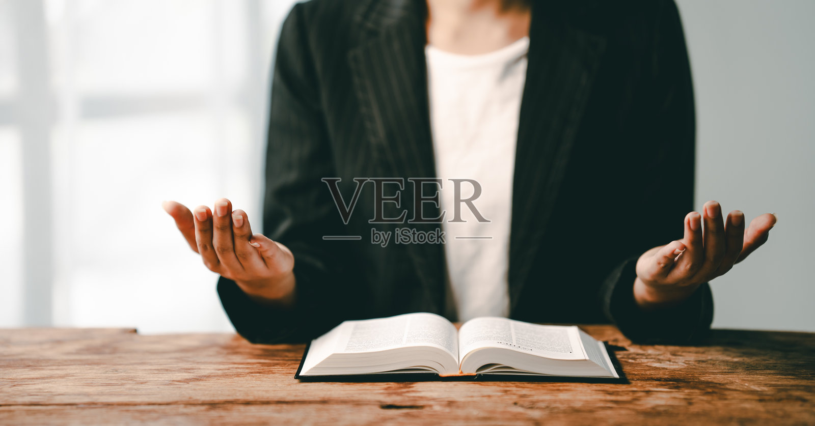 年轻女性在桌子上祈祷并阅读圣经的特写视图，忏悔的概念，与上帝祈祷和交谈。照片摄影图片