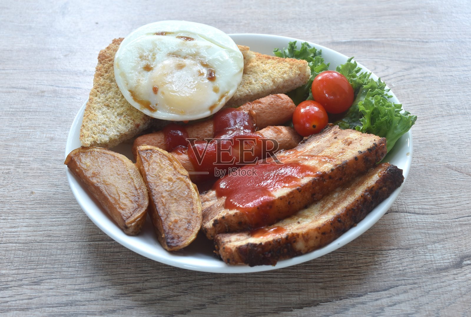 早餐套餐，配有切片肥猪肉和香肠，淋上番茄酱，搭配煎蛋、几片生菜和番茄。照片摄影图片