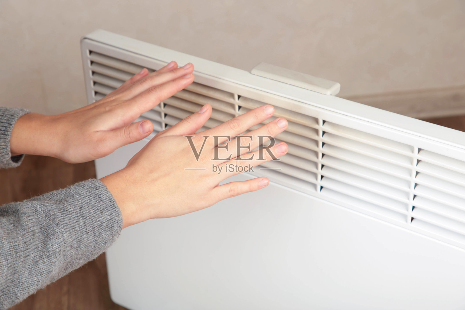 年轻女性在现代电暖器旁取暖。可留白以便添加文字。照片摄影图片