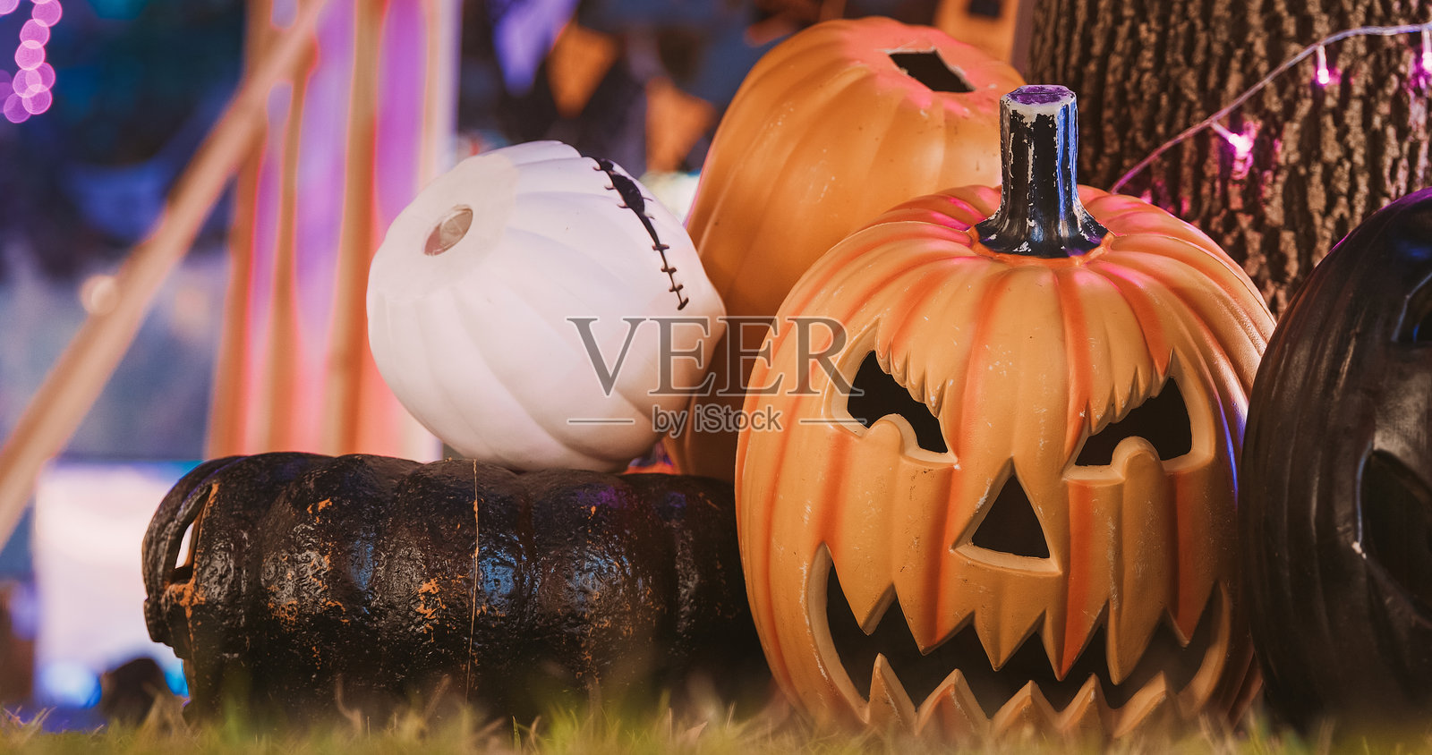万圣节假期。万圣节南瓜灯的传统。草地上的万圣节背景，带有灯笼和南瓜。发光的南瓜灯和蜡烛灯的万圣节装饰概念。照片摄影图片
