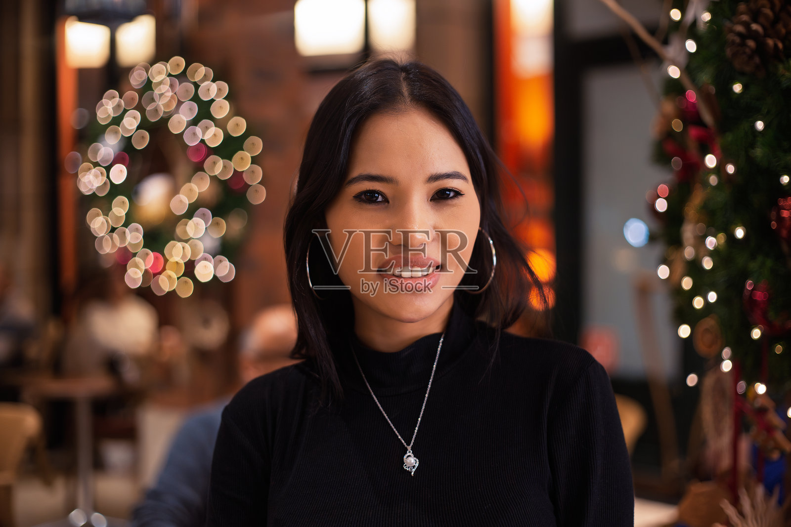 年轻女性在装饰有圣诞节装饰的咖啡馆里微笑照片摄影图片