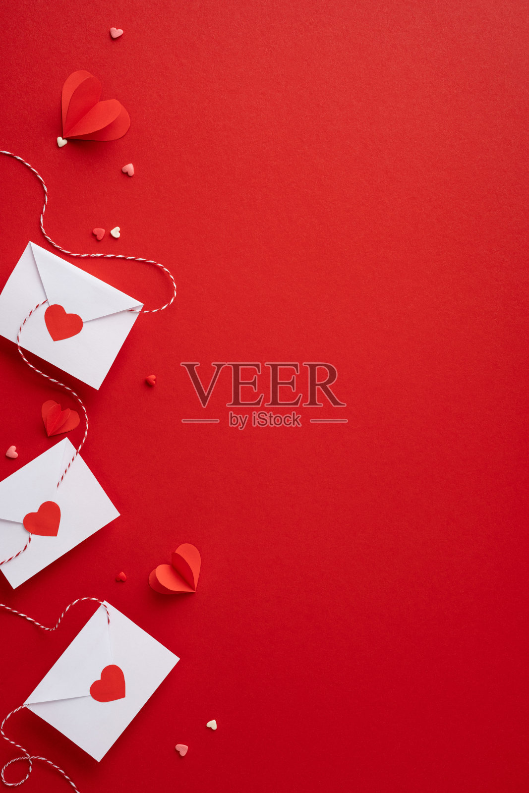 浪漫的垂直情人节信封，装饰着红色心形图案，背景为鲜艳的红色，唤起爱与温情。照片摄影图片