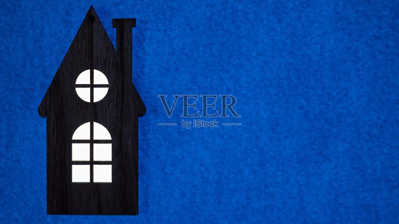 深海军蓝背景上的黑色房屋图形，留有空白区域。照片摄影图片