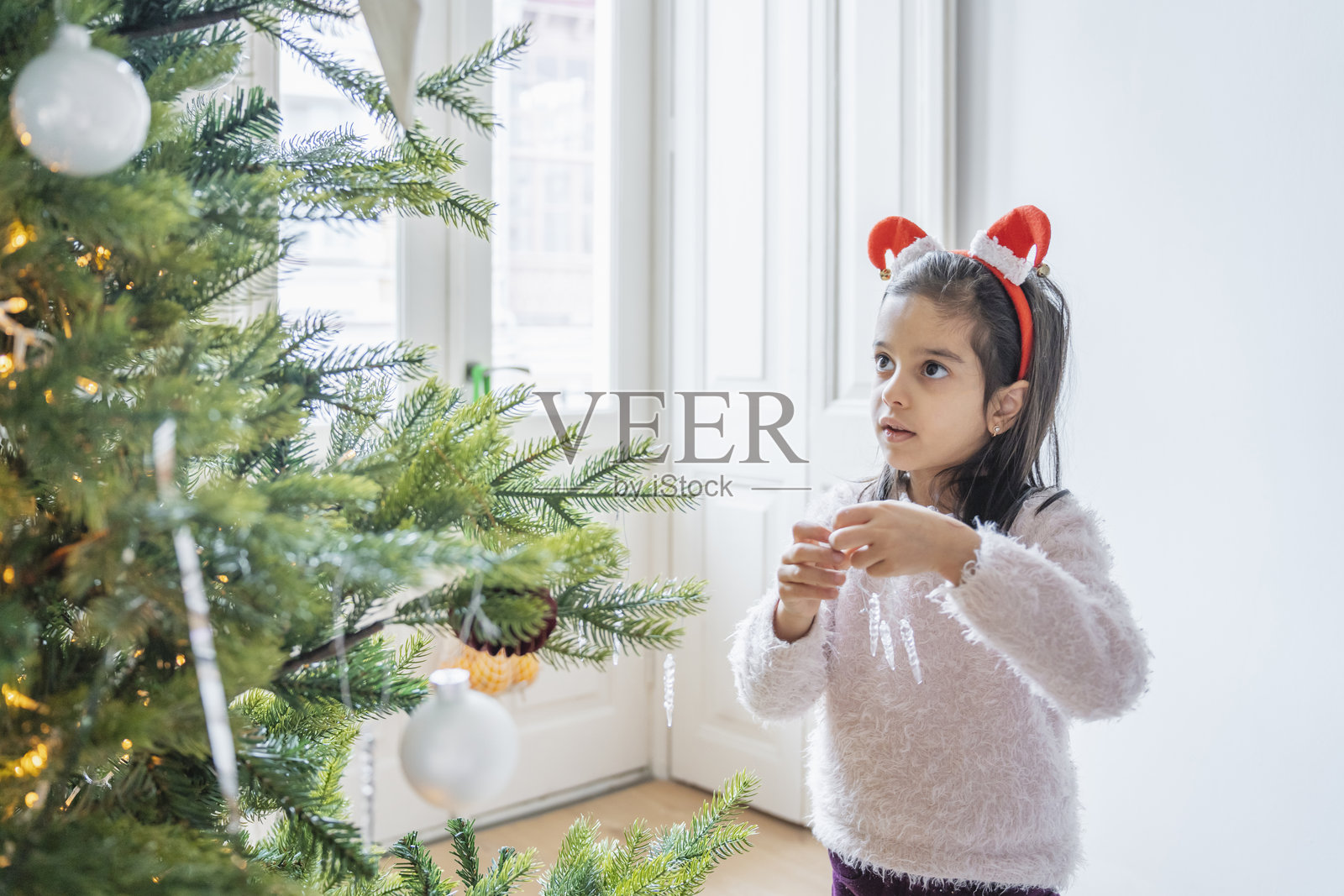 孩子们在节日的圣诞树旁点燃烟花棒。期待圣诞节和新年的快乐时刻，节日气氛浓厚。照片摄影图片
