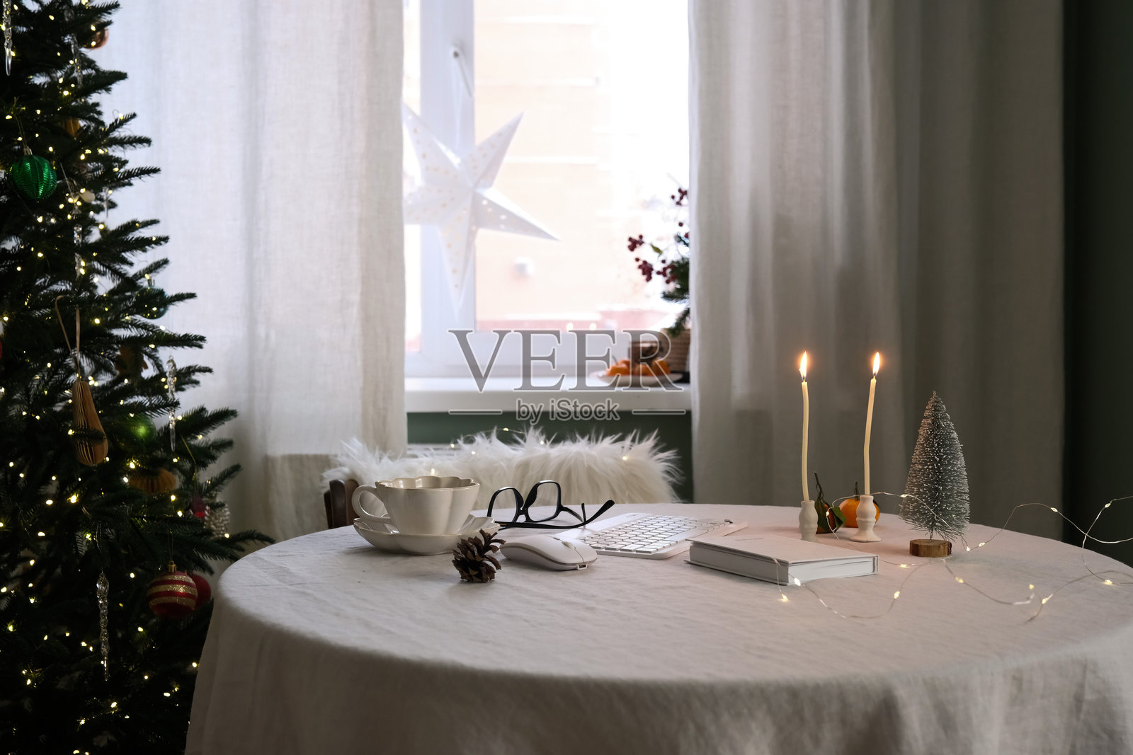 一个舒适的家庭办公室布置，配有笔记本、键盘、节日装饰和温暖的饮品，以提升氛围。照片摄影图片